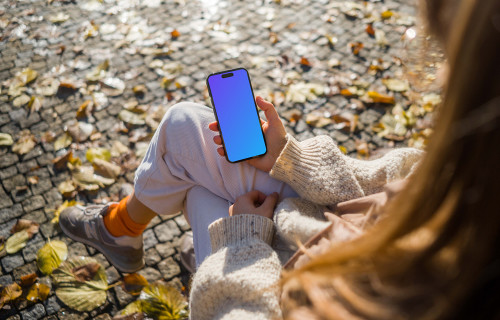 Woman holding an iPhone in autumn theme mockup