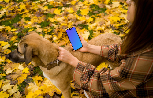 Woman holding an iPhone while scratching a dog in autumn mockup