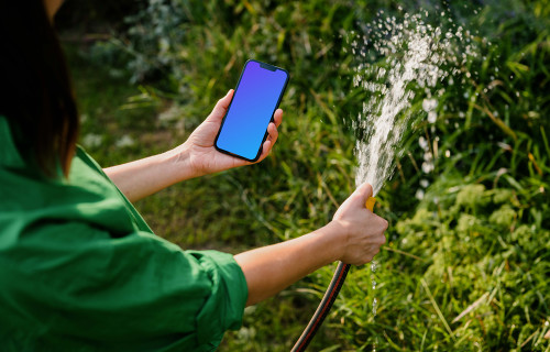 Mujer con un iPhone en la mano mientras riega las plantas mockup