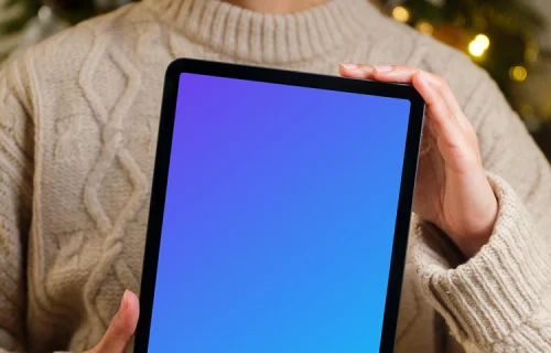 Mujer con iPad mockup junto al árbol de Navidad