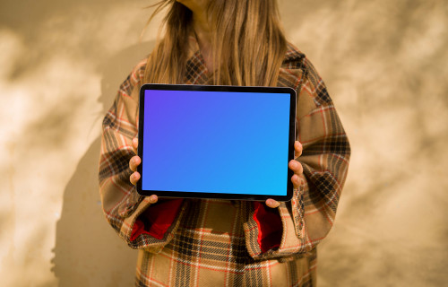 Mujer con abrigo de otoño sosteniendo un iPad Air mockup