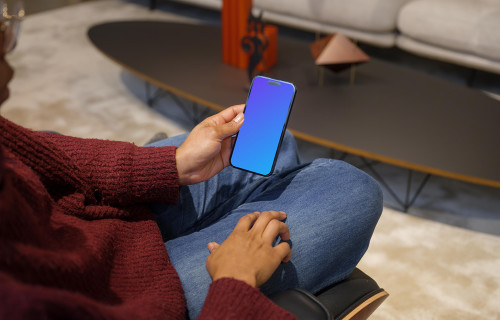 Woman in burgundy sweater holding an iPhone 14 Pro