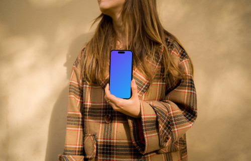 Mujer con abrigo sosteniendo un iPhone 14 Pro mockup