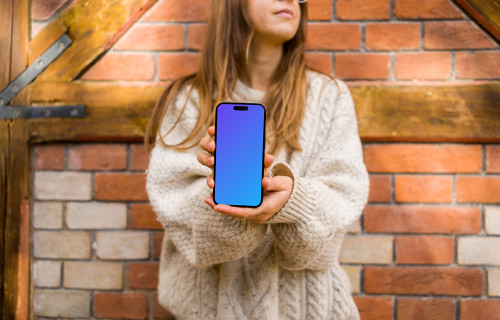 Woman in sweater holding an iPhone 14 Pro mockup