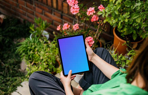 Woman sitting in garden while holding an iPad Air mockup