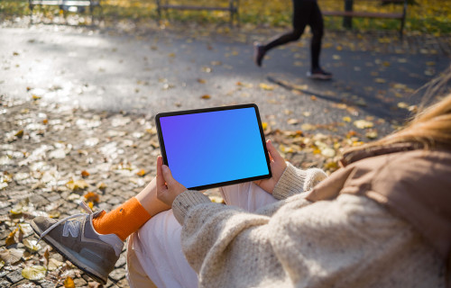 Woman sitting on a bench holding a tablet mockup