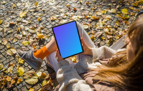 Mujer sentada en un banco con un iPad Air en la mano mockup