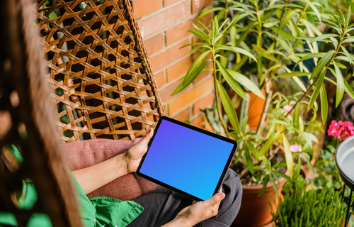 Woman sitting on a hammock while holding an iPad Air mockup