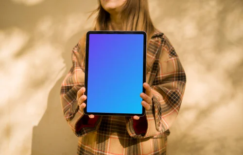 Woman standing in front of wall holding an iPad Air mockup