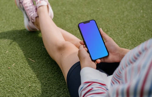 Mujer joven con un smartphone en la mano mockup sobre la hierba