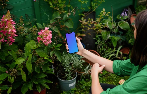 Female holding an iPhone mockup with flowers in the background