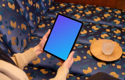 Female holding iPad mockup in colorful lounge setting