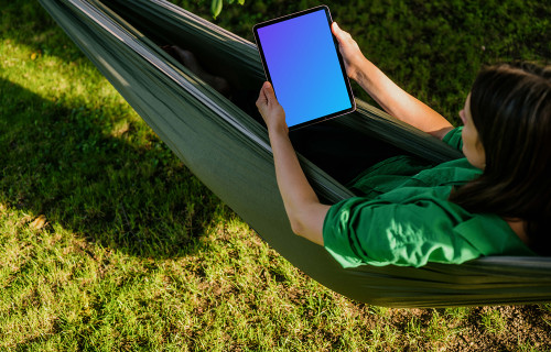 Female laying in hammock while holding a tablet