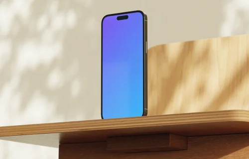 Free iPhone mockup on a wooden desk in sunlight