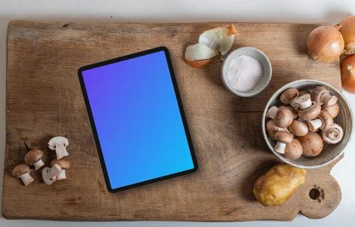 iPad and mushrooms on a wooden chopping board