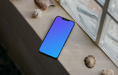 iPhone 13 Pro mockup by a window beside some seashells