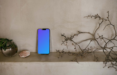 iPhone 13 Pro mockup next to a teapot and shrub