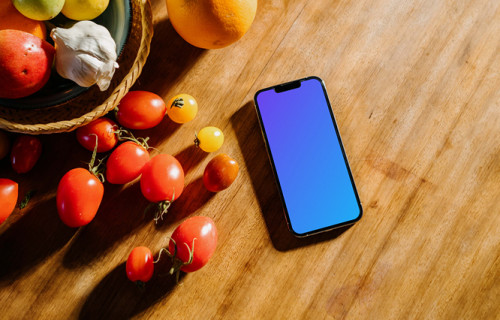 iPhone 13 Pro mockup on a table next to a bowl of fruits