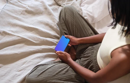 iPhone 15 Pro mockup in a woman's hands on cozy bedding