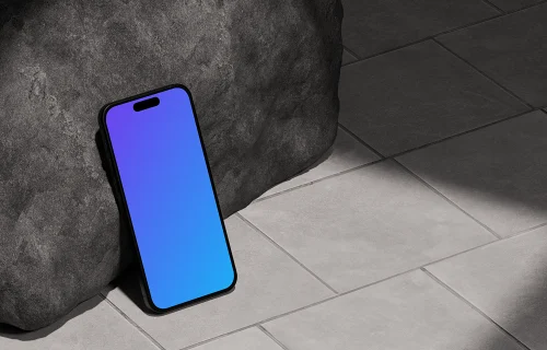 iPhone 16 mockup leaning against a rock on tiled floor
