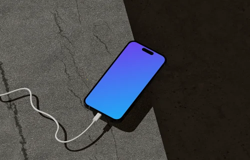 iPhone 16 Mockup on Concrete Surface with Charging Cable