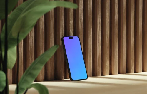 iPhone mockup on a wooden surface with a plant