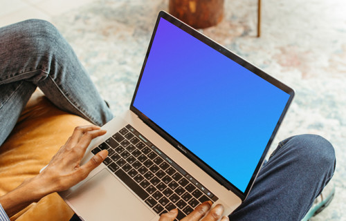 Male user sitting on a chair and using a MacBook Pro mockup