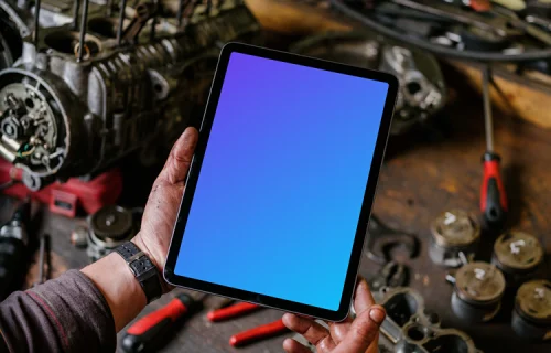 Man holding up an iPad Air mockup in front of a workbench