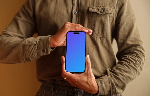 Free mockup of man in khaki shirt holding the iPhone