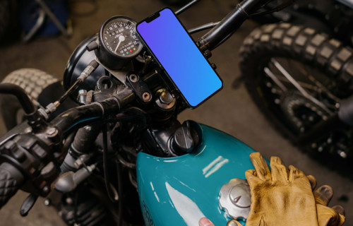 Man with a motorcycle holding an iPhone 13 Mockup