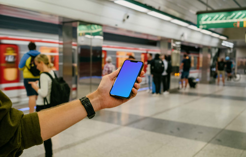 Person's hand holding an iPhone 13 mockup