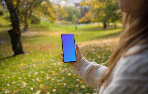 Woman hand holding a phone mockup in the autumn season