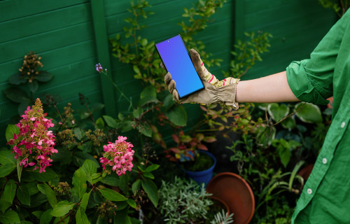 Woman holding a phone in garden gloves mockup