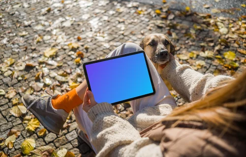 Woman holding a tablet in the park scratching dog mockup