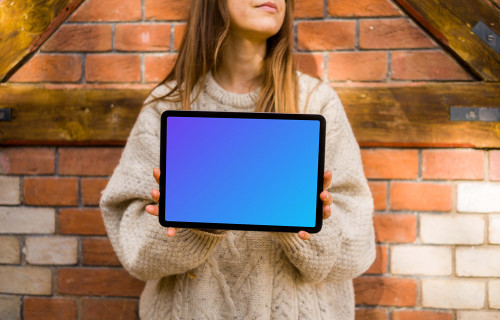 Woman holding an iPad in front of brickwall mockup