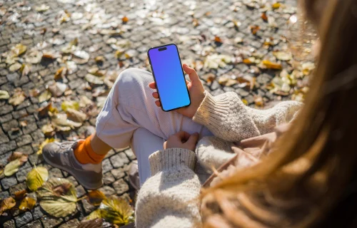 Woman holding an iPhone in autumn theme mockup