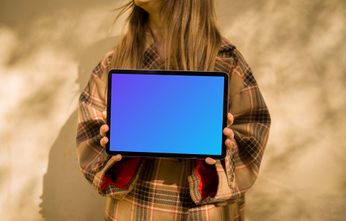 Woman in an autumn coat holding an iPad Air mockup