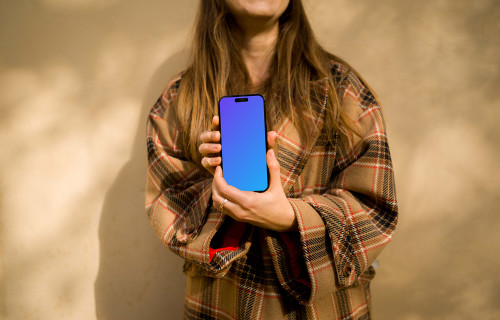 Woman in coat holding an iPhone mockup