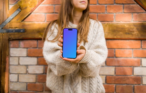 Woman in sweater holding an iPhone 14 Pro mockup