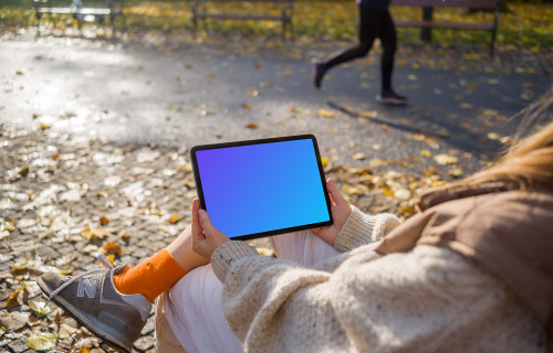 Woman sitting on a bench holding a tablet mockup
