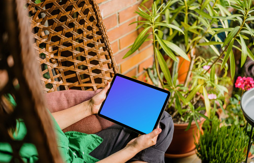 Woman sitting on a hammock while holding an iPad Air mockup