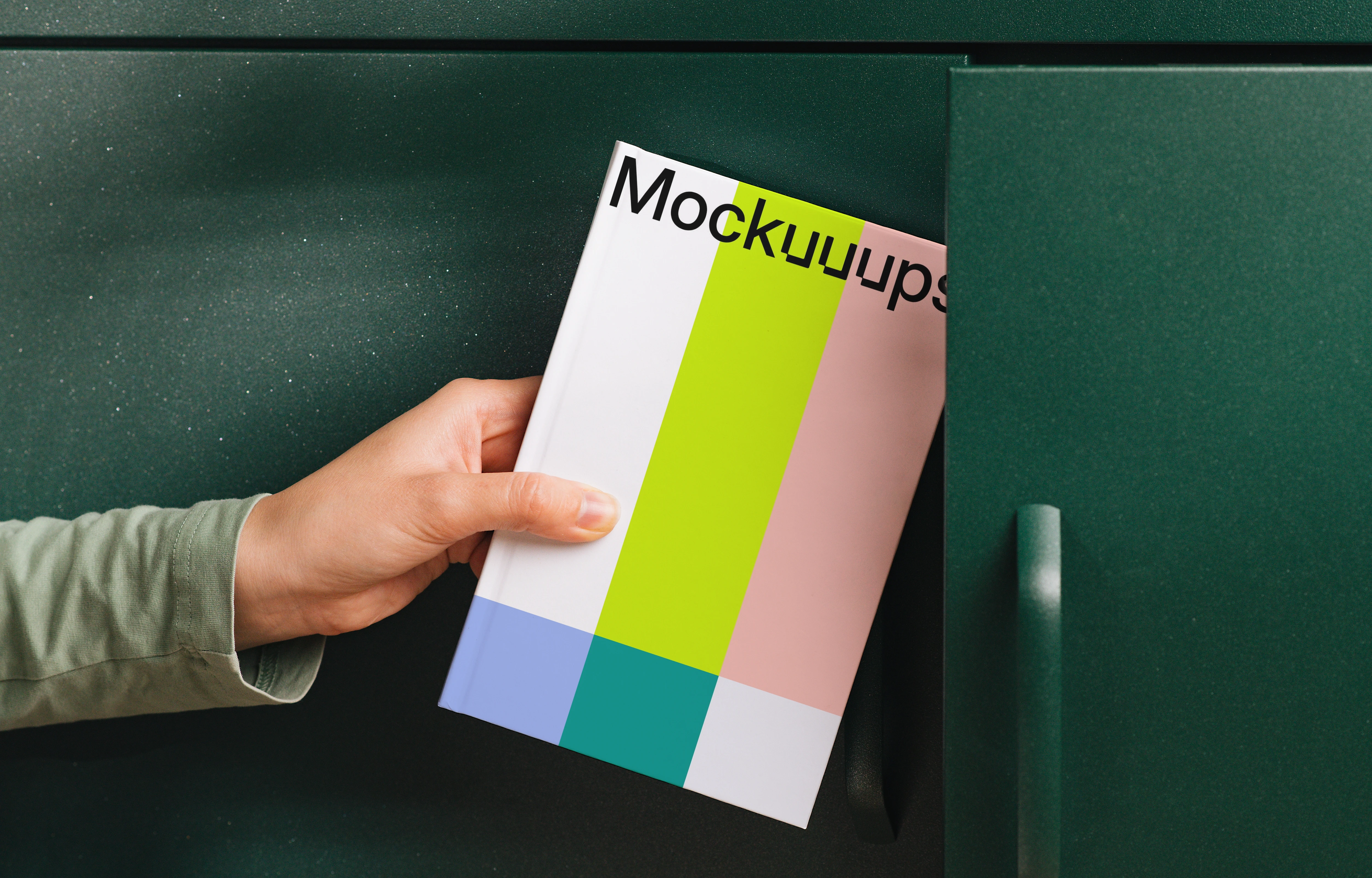 Book mockup held by hand near green cabinet