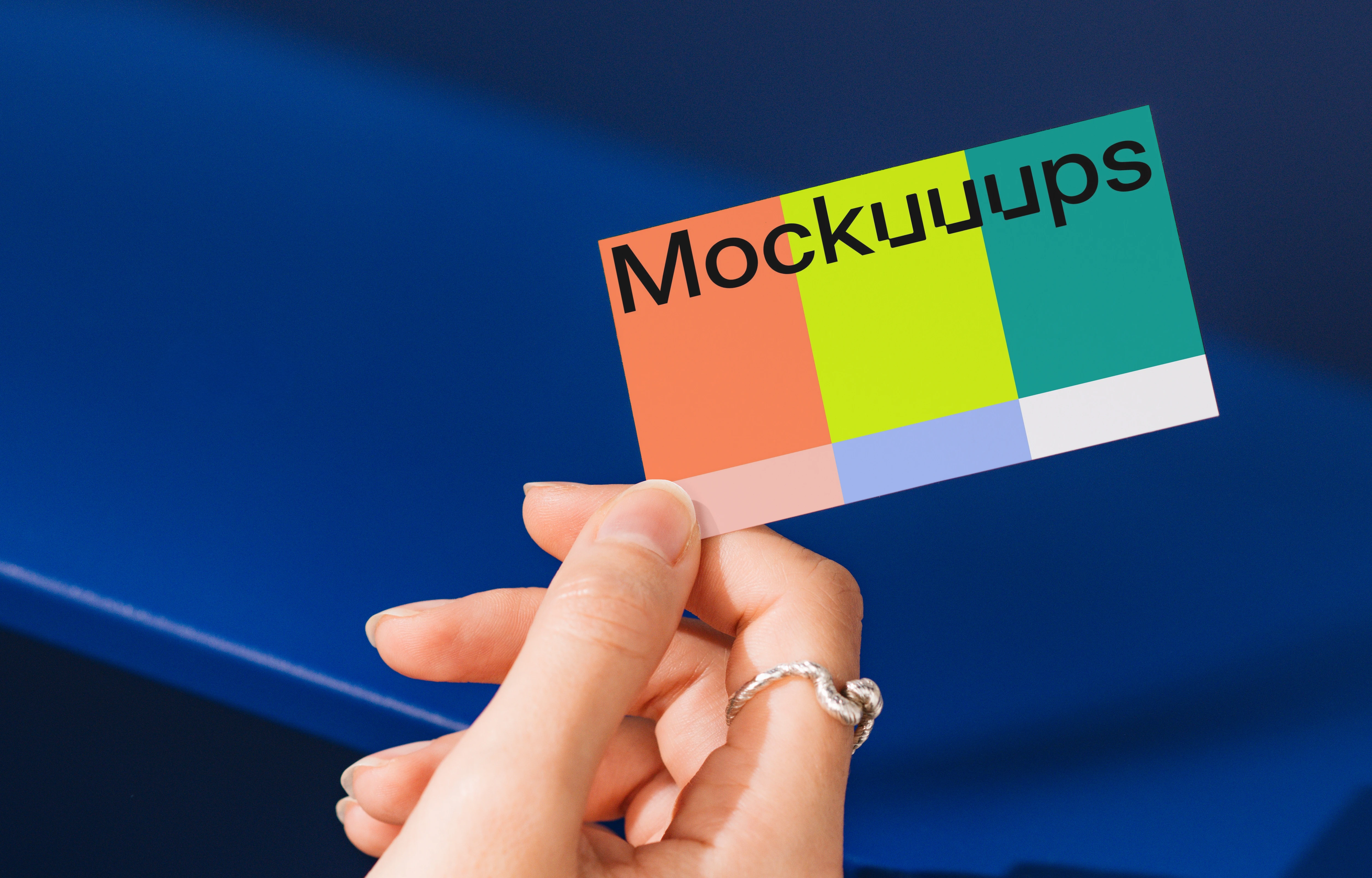 Business card mockup held against a bold blue background