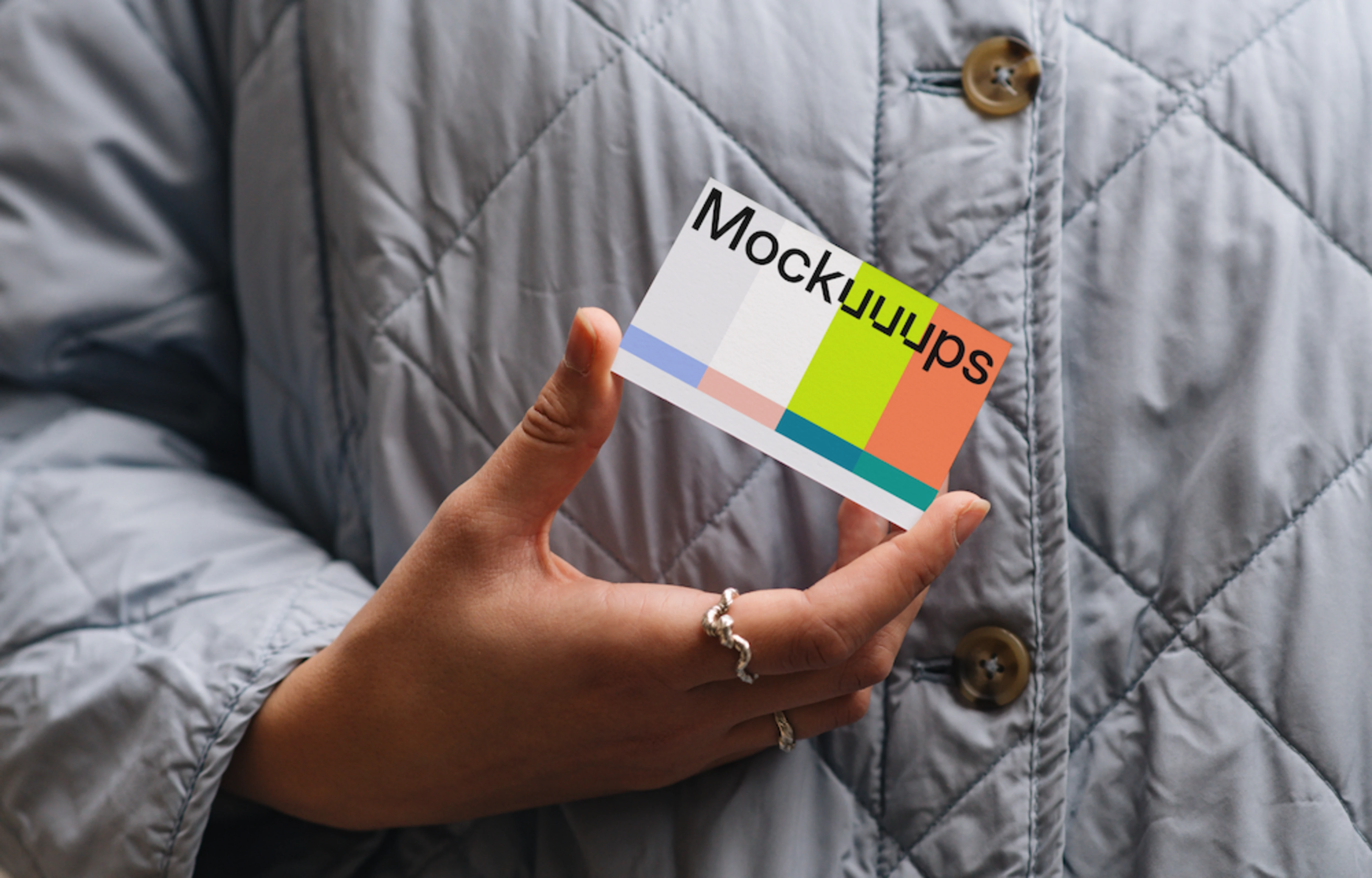 Business card mockup held in hand with a quilted jacket