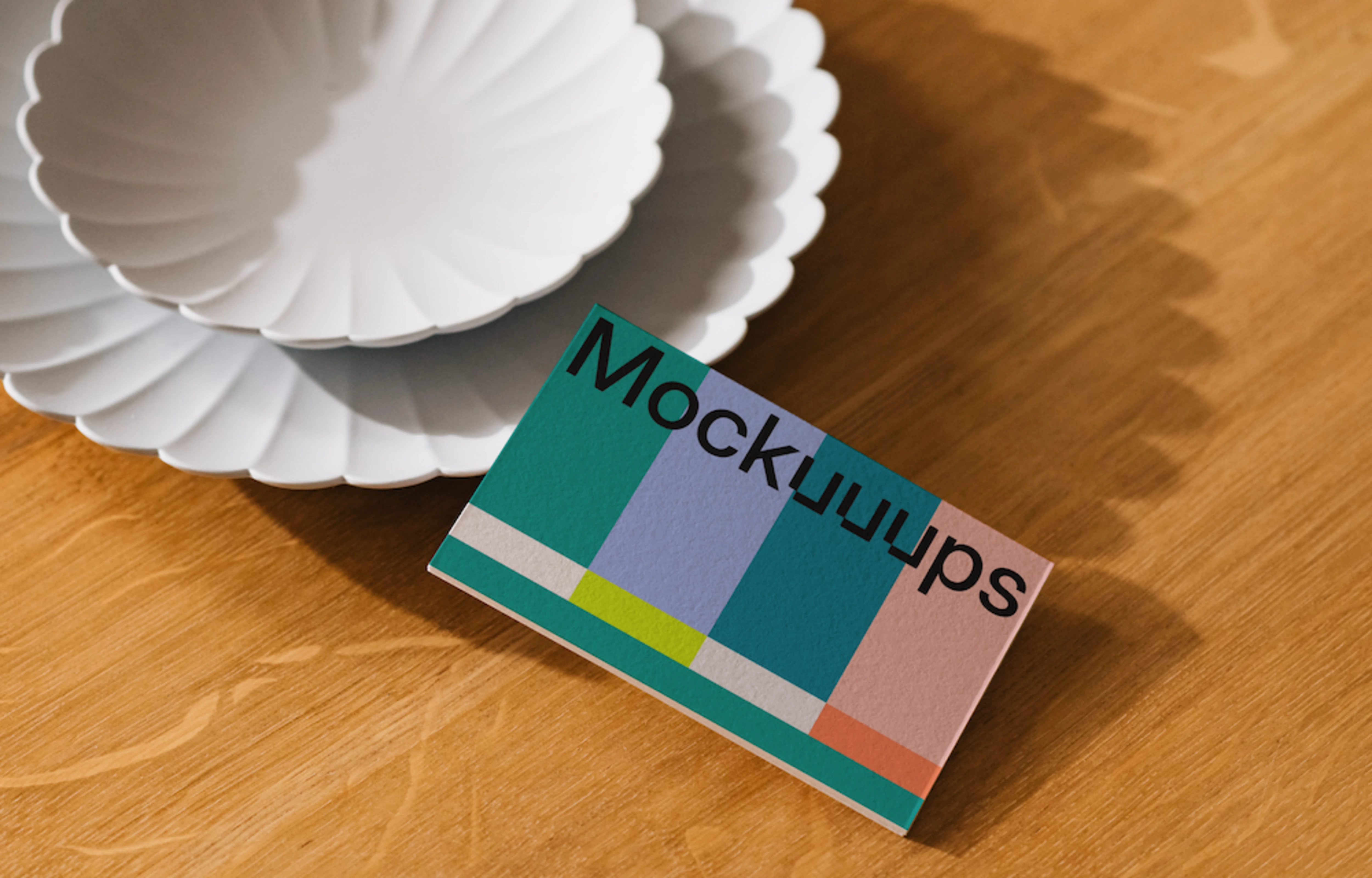 Business card mockup on a wooden table with white plates