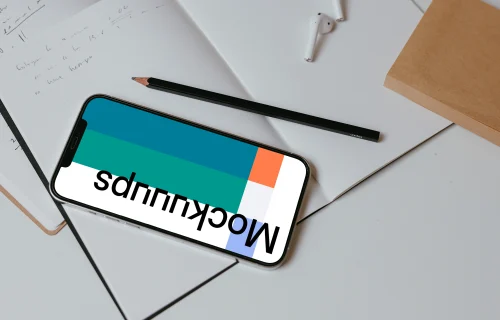 iPhone mockup on a table with books and a wireless keyboard by the side.