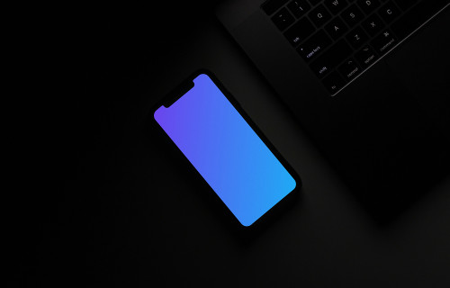 Night iPhone mockup on a table beside a keyboard