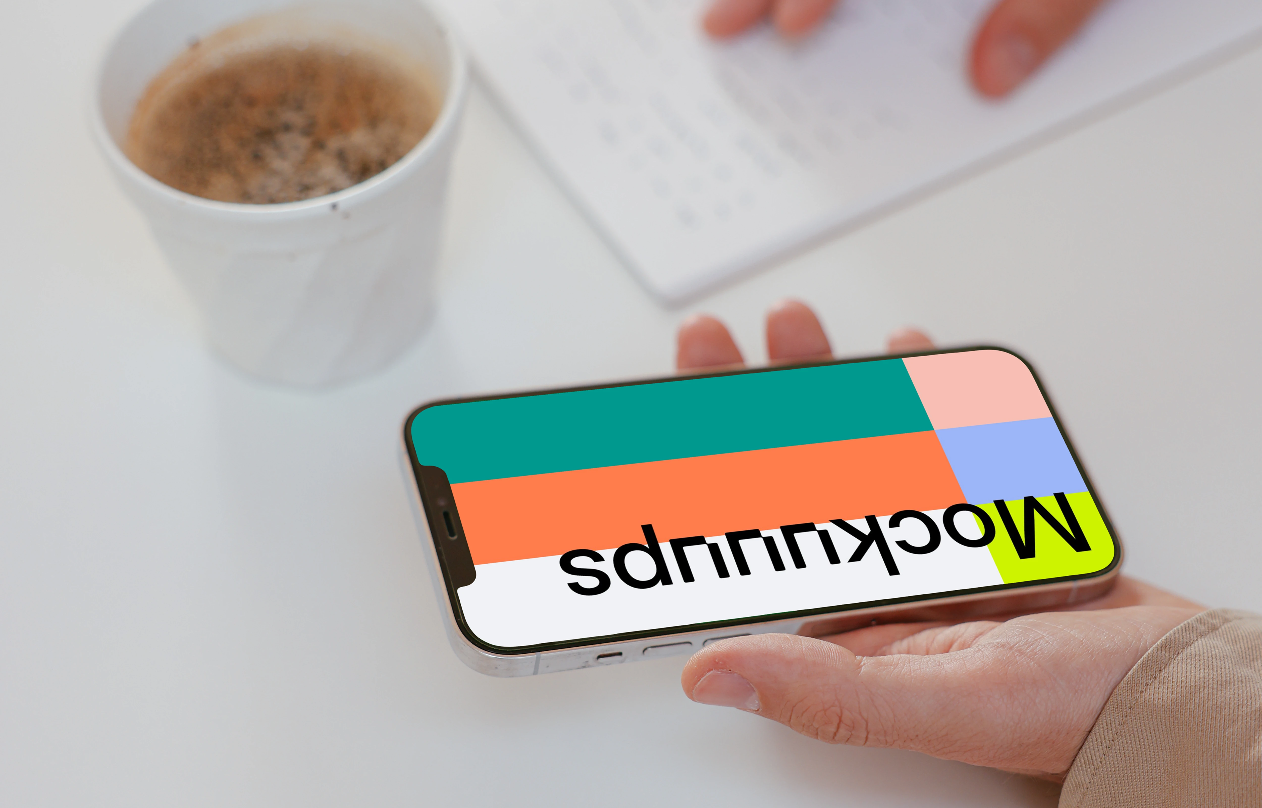 User holding iPhone and writing on a notebook beside a cup of coffee