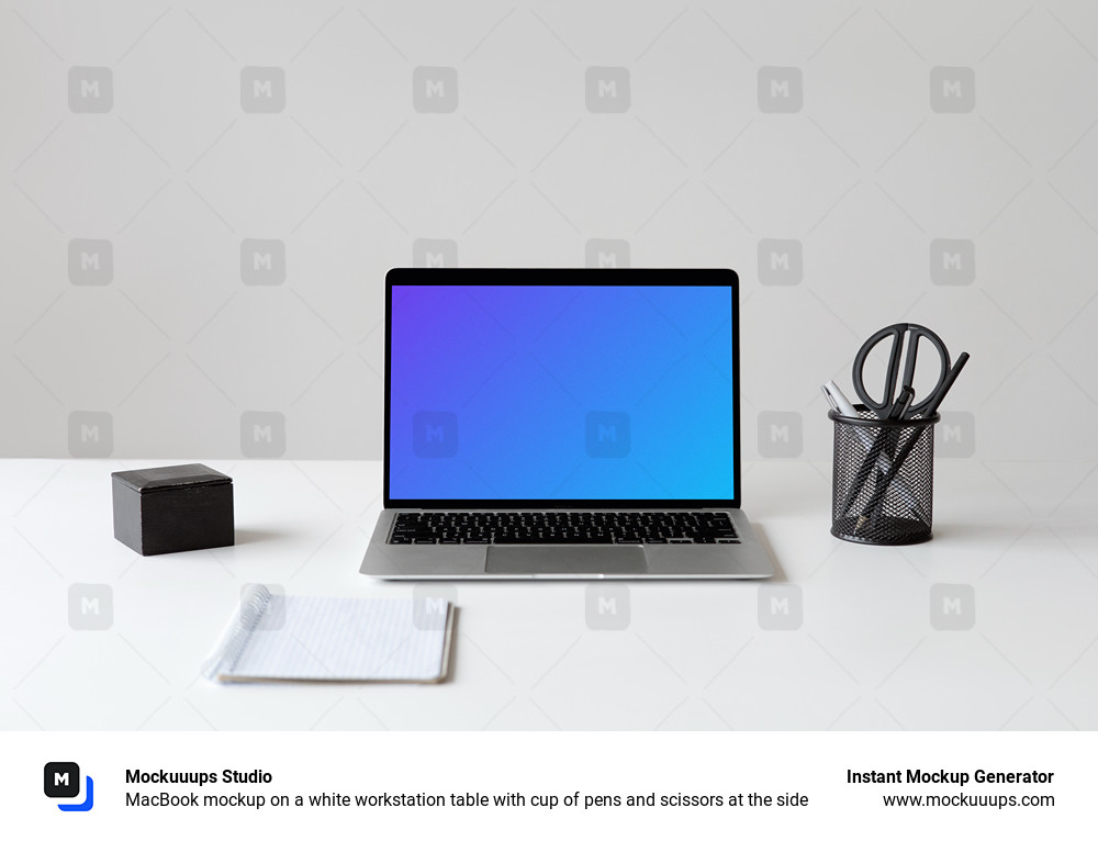 MacBook mockup on a white workstation table with cup of pens and scissors at the side