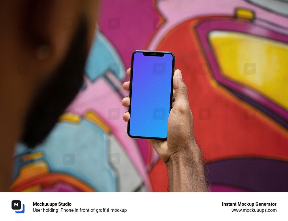 User holding iPhone in front of graffiti mockup